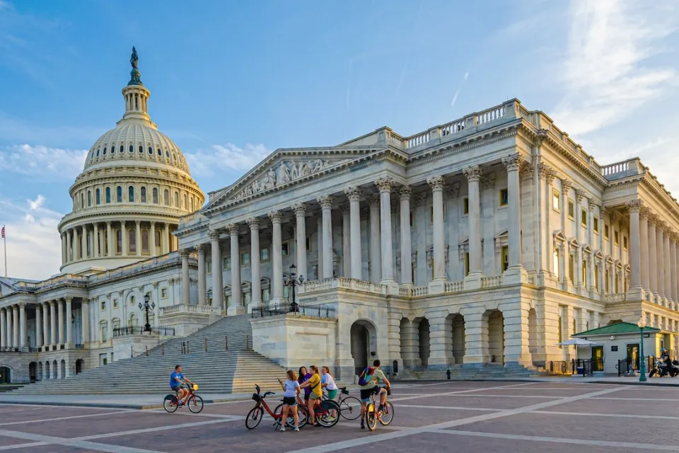 Wide shot of group of people with bikes standing in plaza near U.S. Capitol in Washington, D.C.